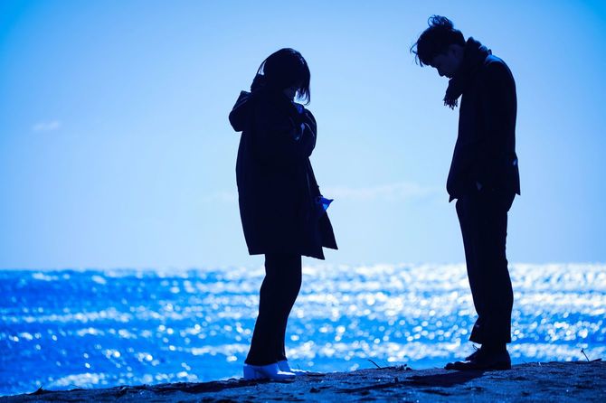 海辺でうつむく男女のカップル