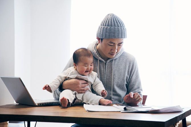 彼は仕事をしていて、家で育児をしています。