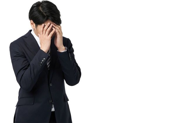 手で顔を覆っている男性