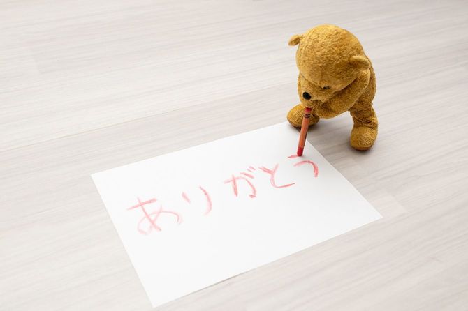 紙にクレヨンでありがとうと書くテディベア