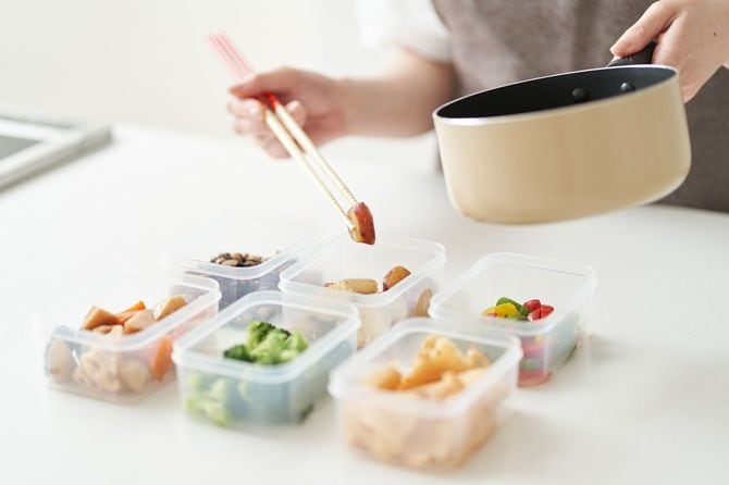作り置きをタッパーに入れている女性の手元
