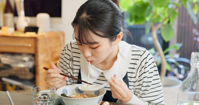レストランでラーメンを食べている若い女性