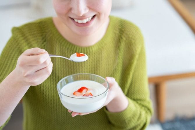 イチゴの入ったヨーグルトを食べる人