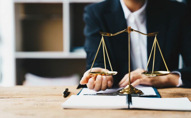 天秤に手を添える弁護士