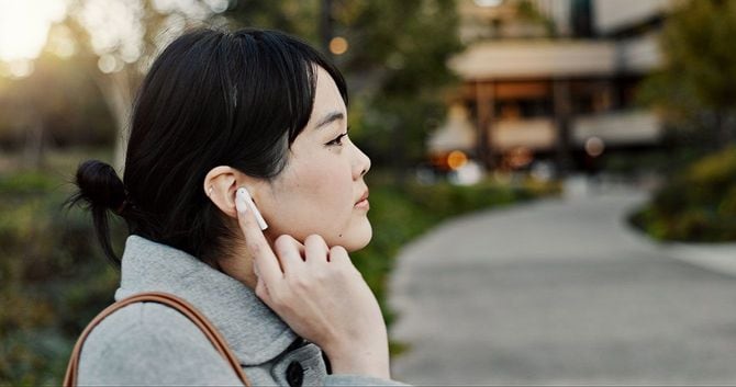 イヤホンで何かを聴いている女性