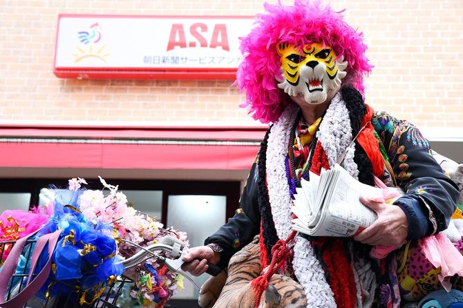 朝日新聞のステーション前でピンクアフロのカツラにタイガーのお面をつけた人