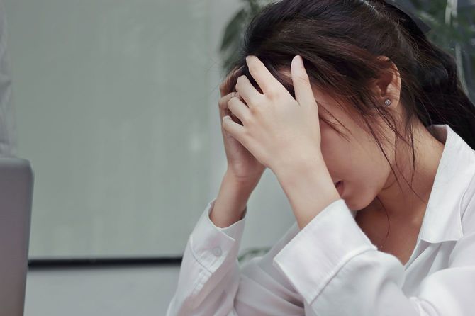 頭を抱えてうつむく女性