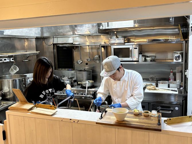 息の合った動きでラーメンを完成させる田中貴志さんと妻の有香さん