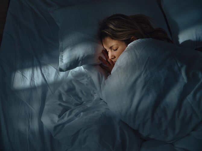 夜にベッドで寝ている女性