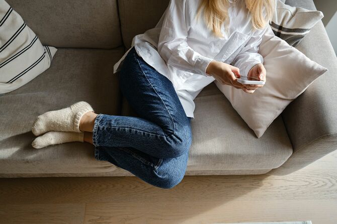 ソファでスマホを見る女性