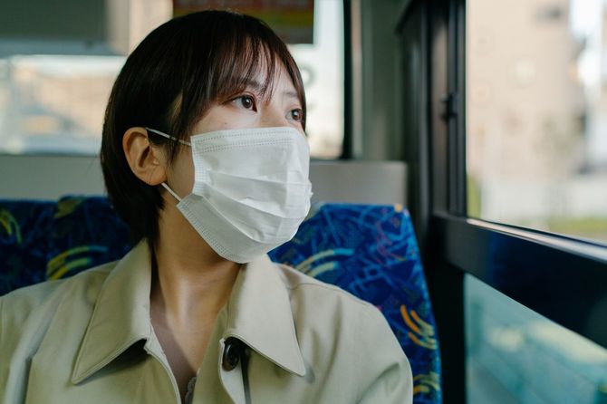 マスクを着用し、バスで通勤するビジネスウーマン