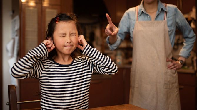 お母さんに叱られて耳をふさぐかわいい女の子