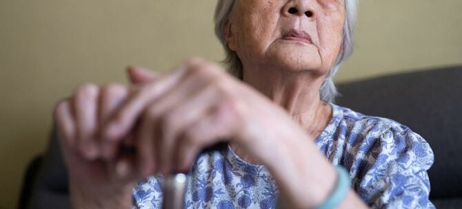 杖に手をかけて座っているシニア女性