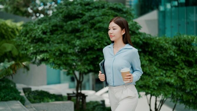 タブレットとコーヒーを手に仕事に向かう女性