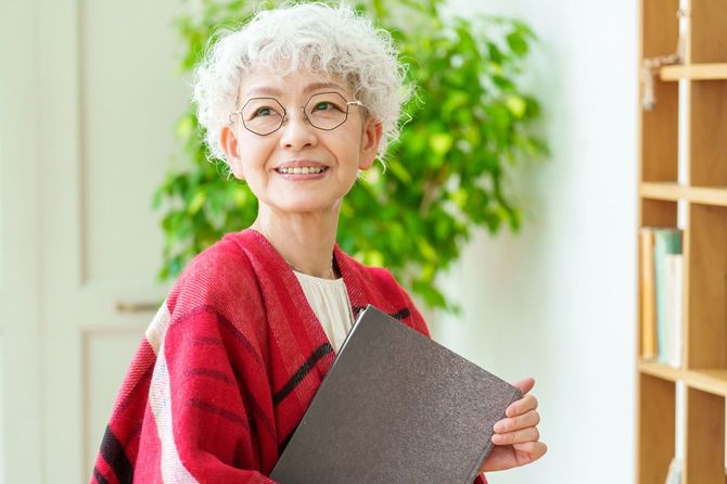 本棚の横で本を抱える年配の女性