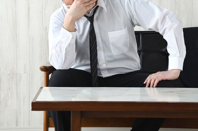 リビングルームで顔を覆うビジネスマン