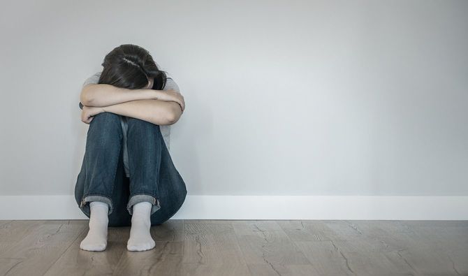 膝を抱えて顔を伏せて床に座り込んでいる女性