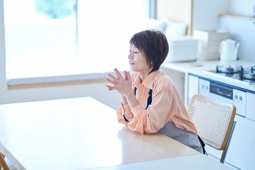 ダイニングの椅子に座るエプロンをつけた女性