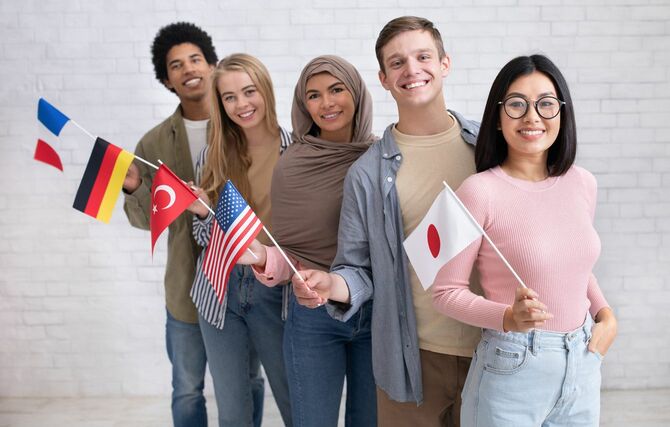 アメリカ、日本、トルコ、ドイツ、フランスの旗を持つ多様な人種の生徒たち