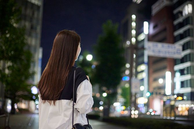夜の街に立つ女性の後ろ姿