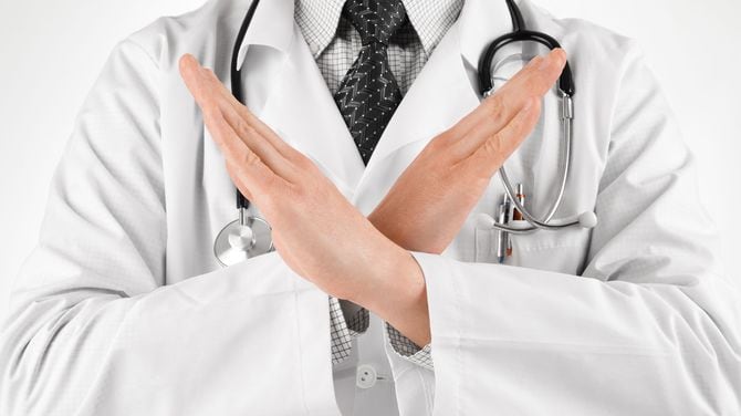 胸の前で腕を交差させバツ印を作る医師