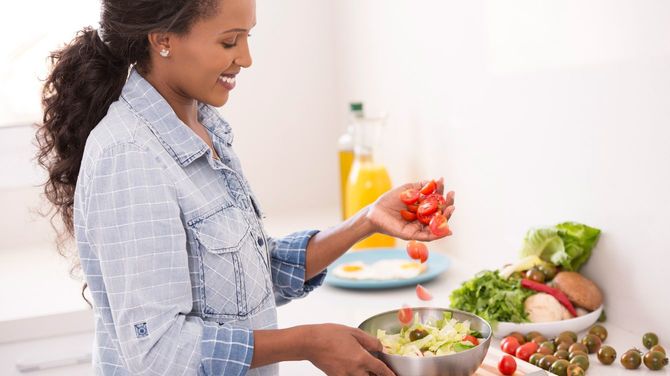 新鮮なサラダにチェリートマトを追加する女性