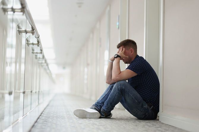 廊下の床に座っている動揺した男