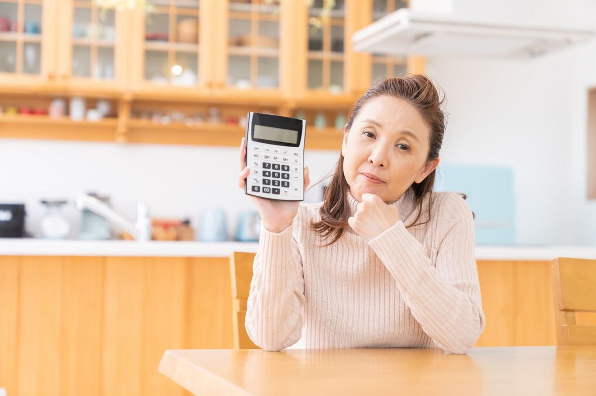 電卓を見せる高齢女性