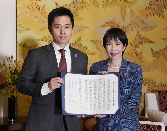 署名した連立政権合意書を報道陣に示す自民党の高市早苗総裁（右）と日本維新の会の吉村洋文代表＝2025年10月20日、国会