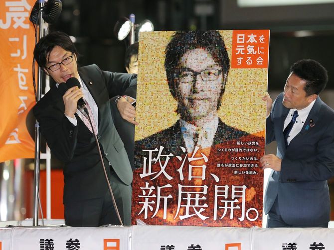 「日本を元気にする会」の屋外党大会で、イメージポスターを発表する松田公太代表（左）＝2015年3月17日、東京都新宿区のJR新宿駅東口前