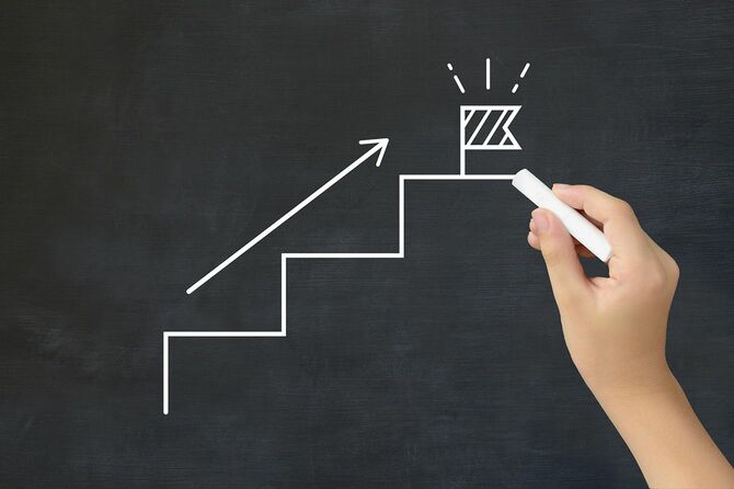 ステップとゴールを描く子どもの手