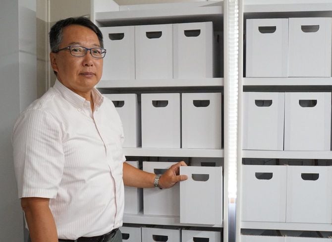 川口徹カワグチマック工業社長。段ボール製整理棚の前で