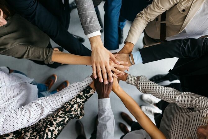 円陣を組んで手を積み重ねる人々