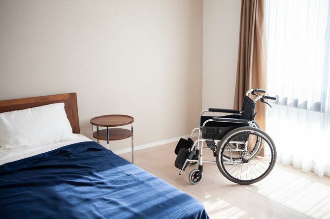日差しの入る部屋に空のベッドと車椅子
