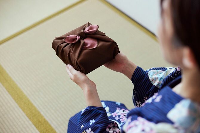 贈り物を示す日本の服を着た女性の手