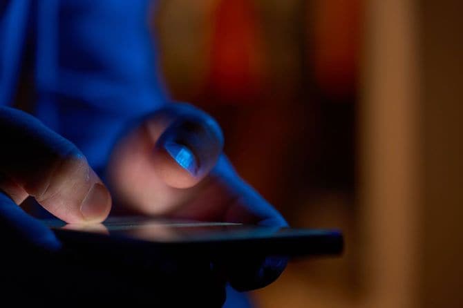暗い部屋でスマホを使用する人の手元