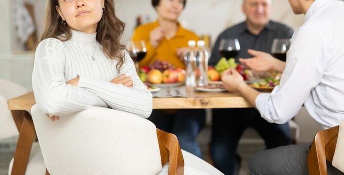 家族の休日のテーブルで両親と動揺している若い女性