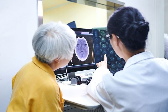 脳のMRI画像を見せながら、高齢の患者に説明をする医師
