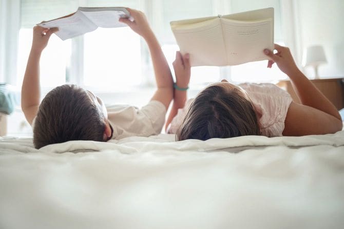寝転んで本を読む子ども2人