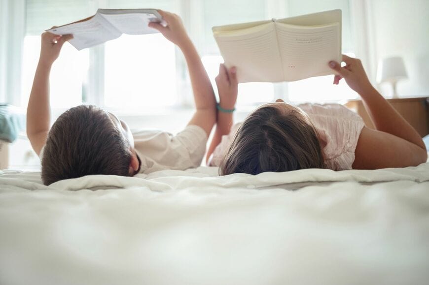 寝転んで本を読む子ども2人