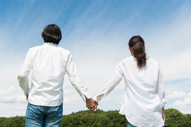 青空の下で手をつないでいるカップル