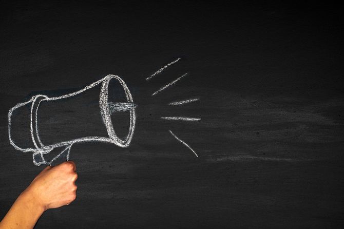黒板に描かれた拡声器を持つ手