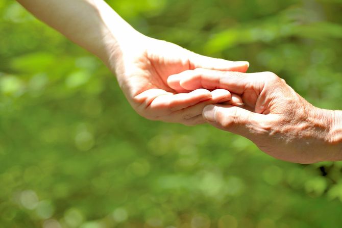 老人の手をとる介護者の手