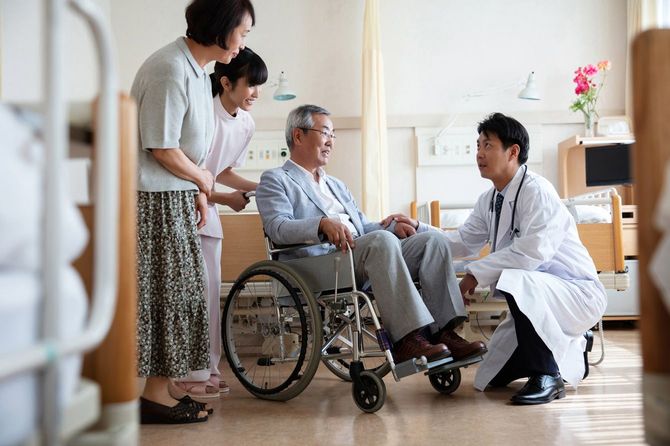 車いすの入院患者と話す医師