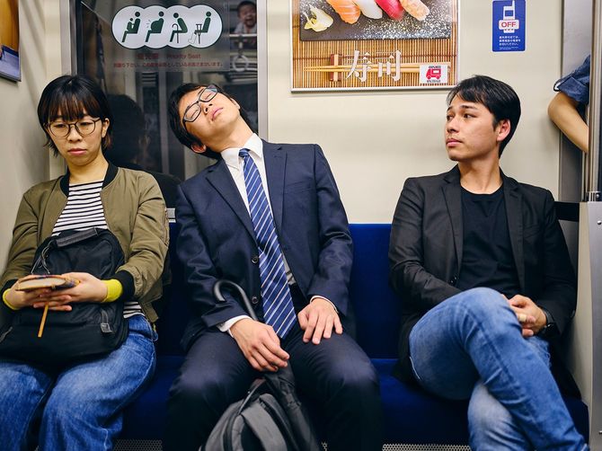 日本の地下鉄車内で居眠りする人