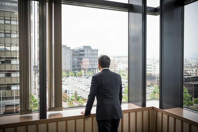 オフィスの窓から外を眺める男性