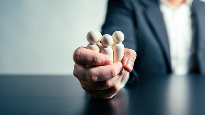 人の形の木のブロックを複数握っている男性