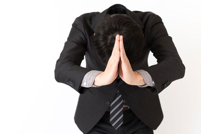 手を合わせて深々と頭を下げるビジネスマン