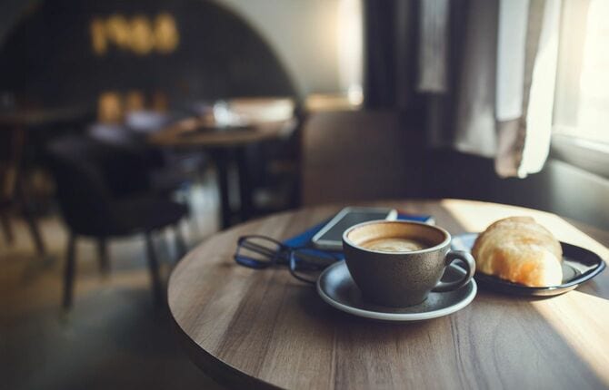 カフェのテーブルに置かれたコーヒー、パン、メガネ