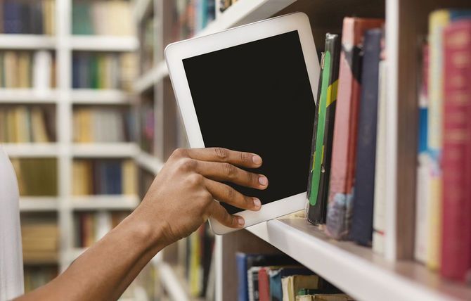 本棚にタブレットを置く人